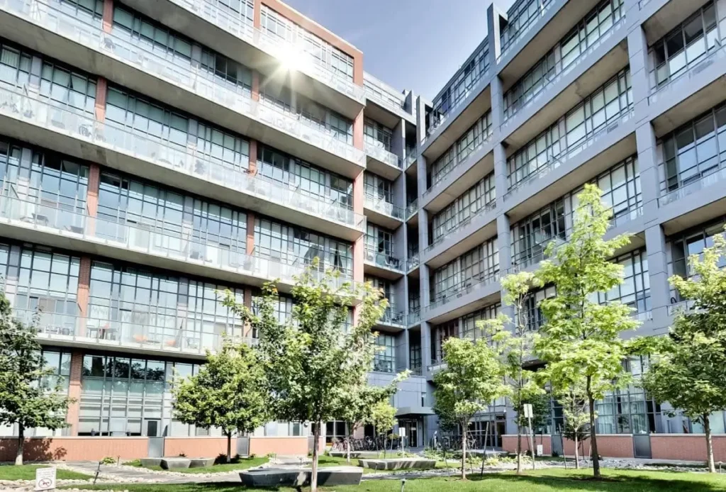 Modern glass-fronted condominium building with landscaped courtyard in Liberty Village Toronto.