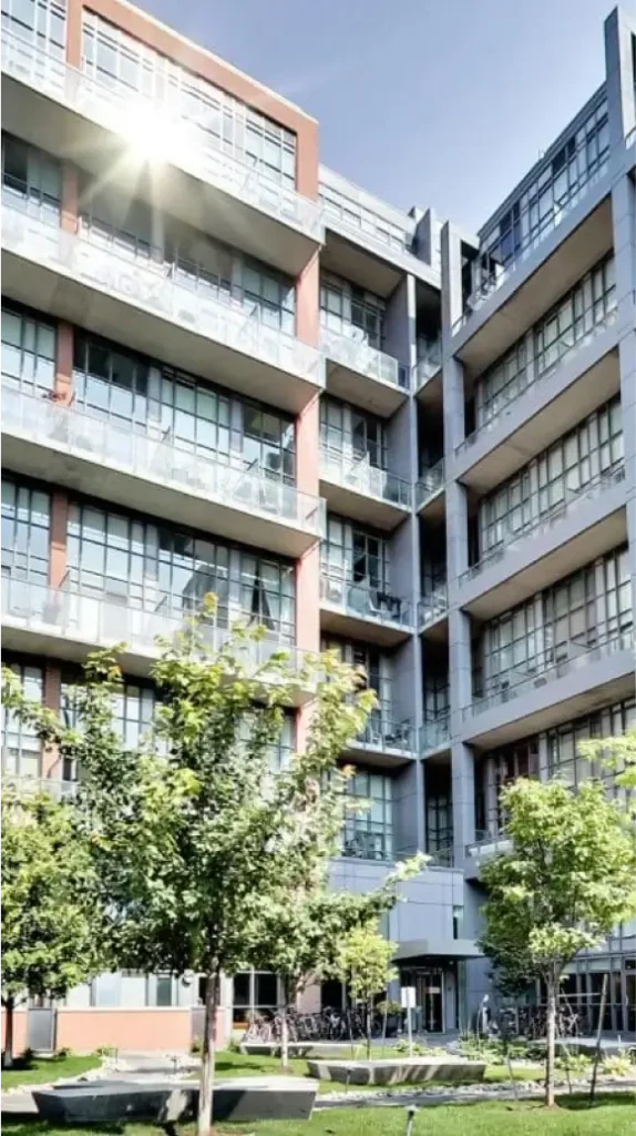 Close-up view of industrial-style condo architecture with tree-lined courtyard in Liberty Village Toronto.